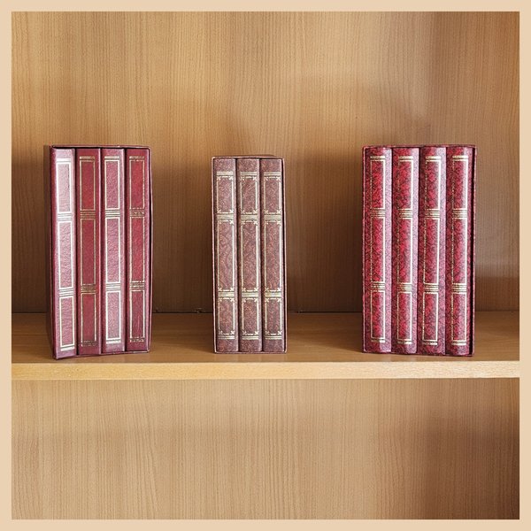 Foto von drei Schubern roter Buchattrappen in einem Bücherregal.