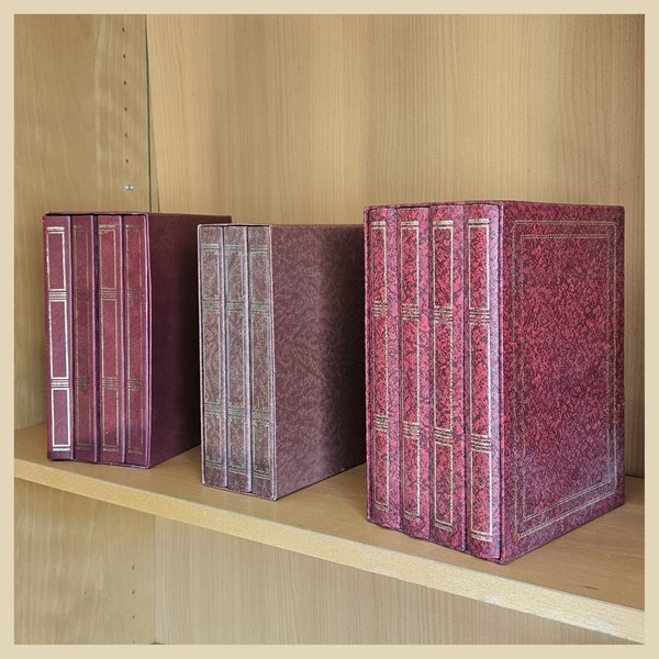 Foto von drei Schubern roter Buchattrappen in einem Bücherregal aus seitlicher Perspektive.
